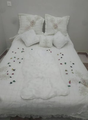 Ein Bett mit weißer Bettdecke, mehreren Kissen und verstreuten dekorativen Blättern.