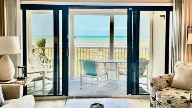 Une chambre d’hôtel dotée d’une grande porte-fenêtre coulissante donnant sur un balcon avec vue sur la plage.