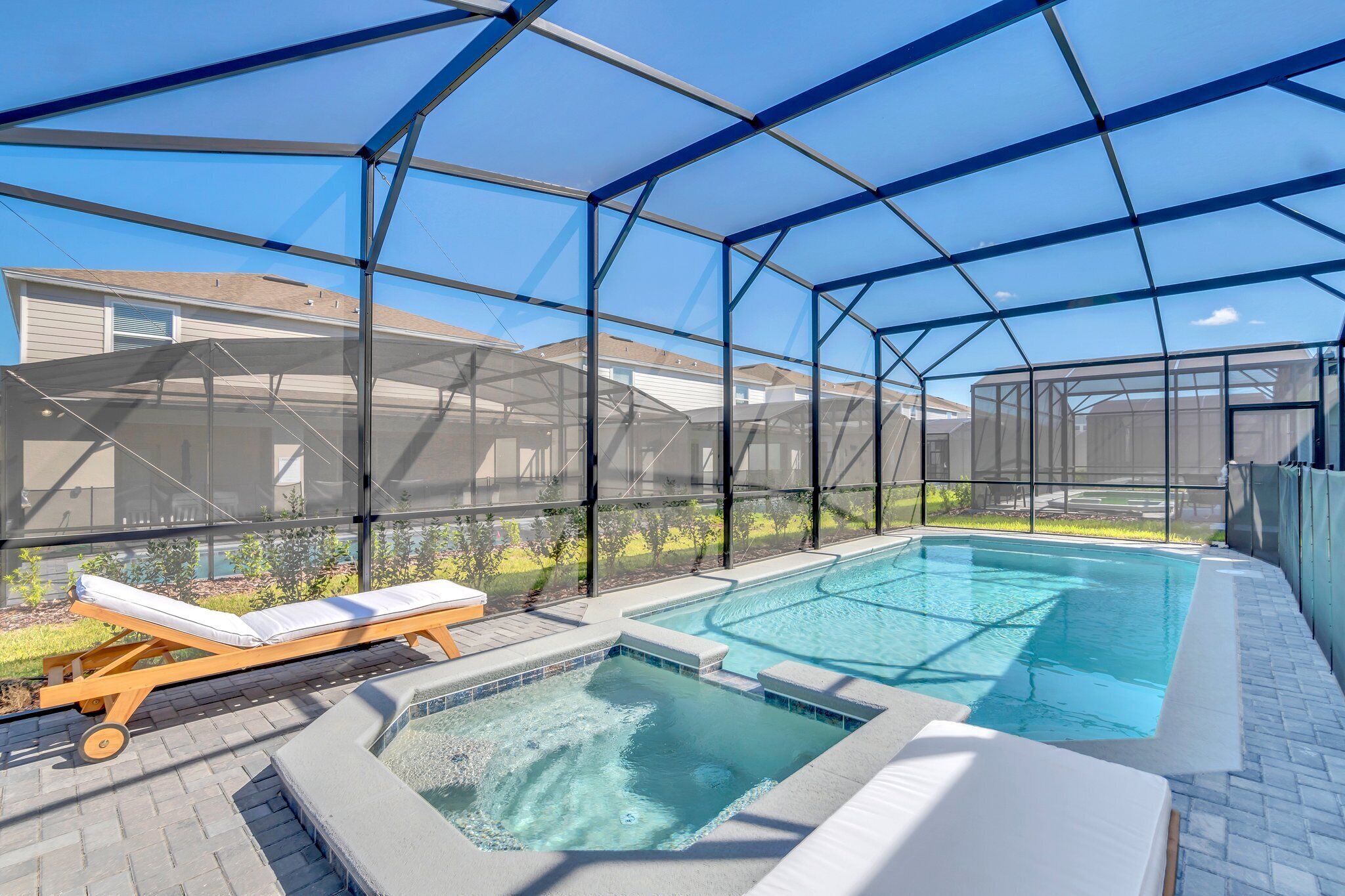 A covered outdoor swimming pool with lounge chairs and a hot tub.
