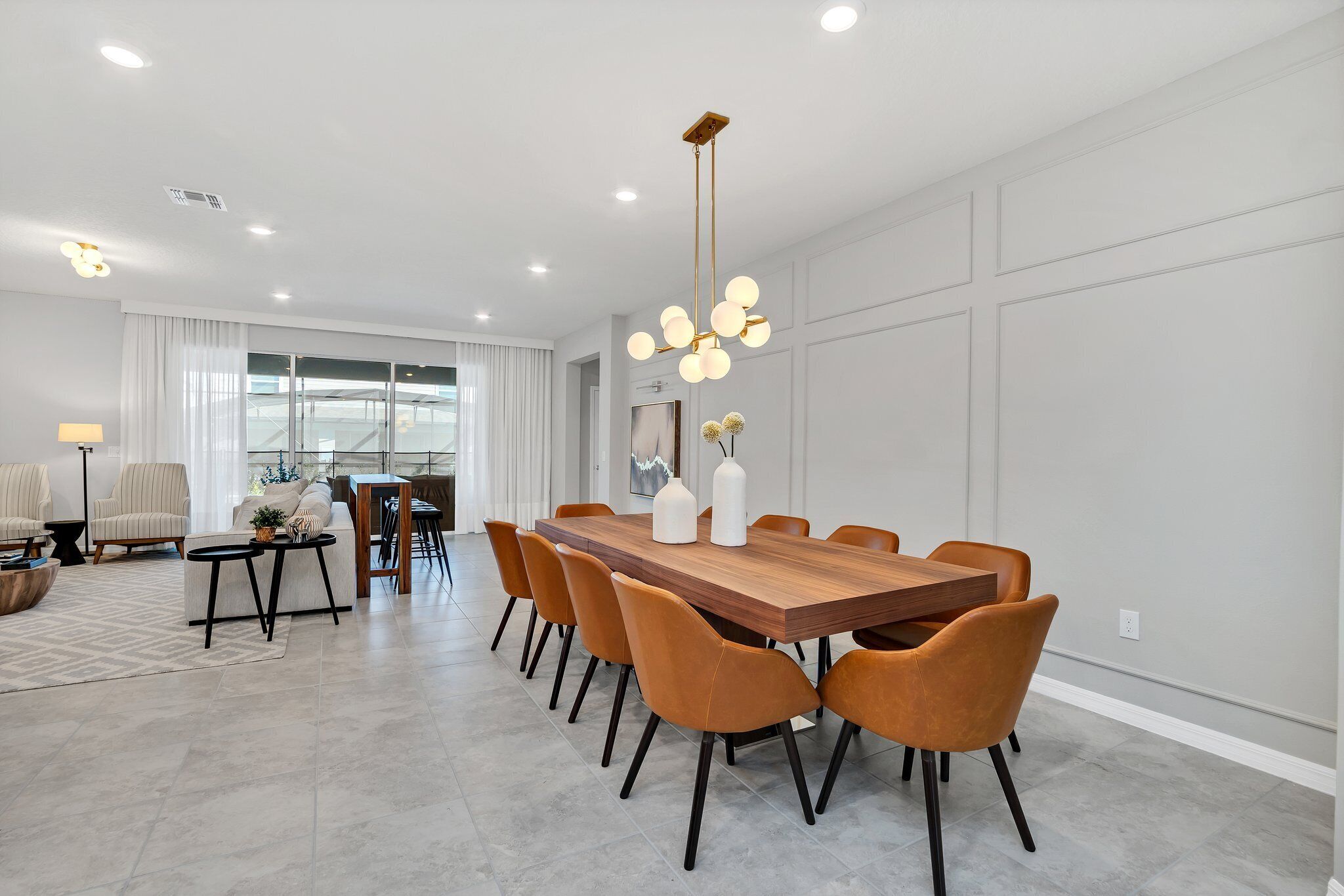 Un espace repas moderne avec une table en bois, des chaises orange et un luminaire suspendu original.