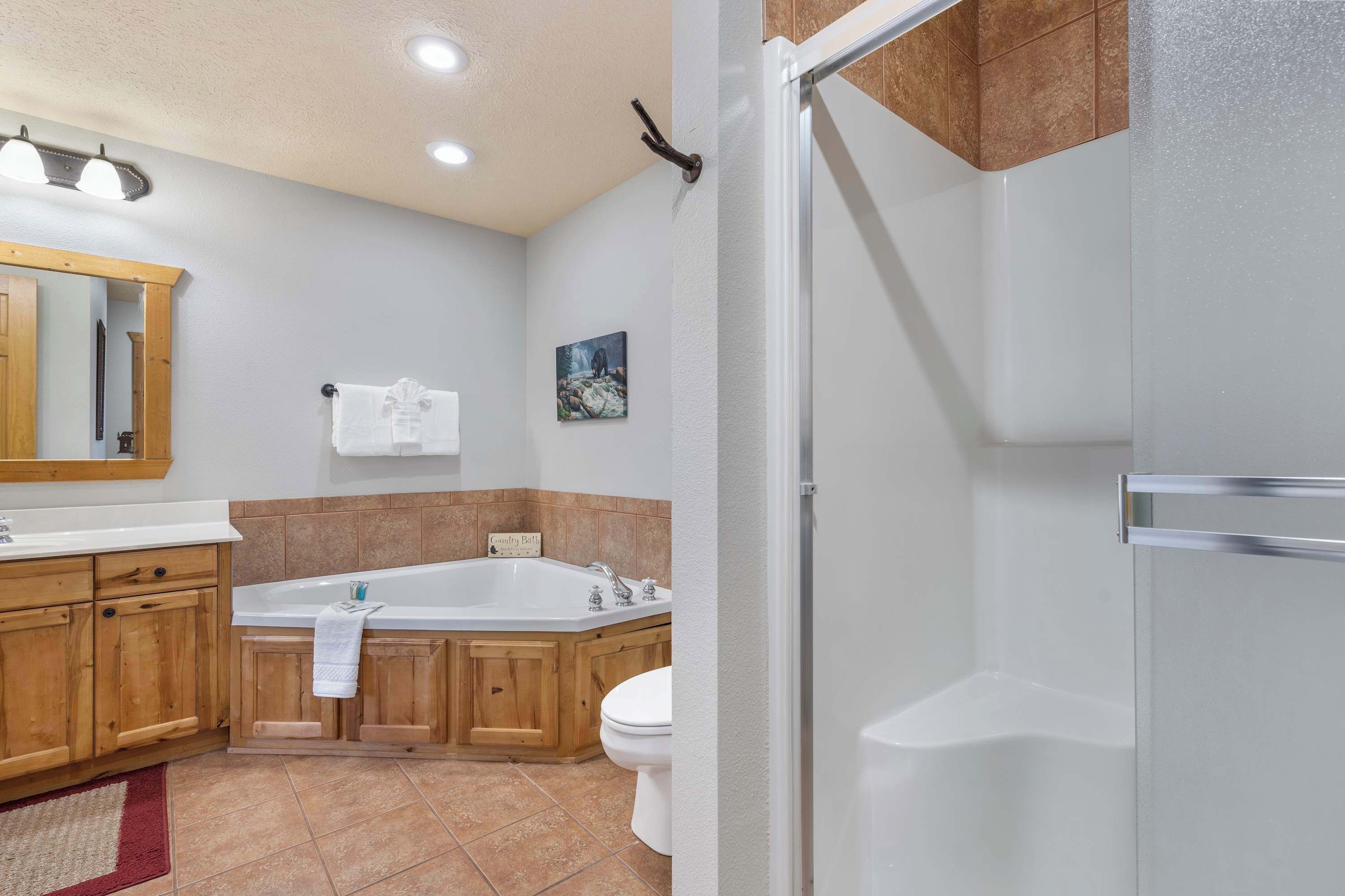 A modern bathroom with a wooden vanity, a large bathtub, and a separate shower area.
