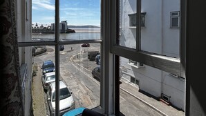 A room with a large window overlooking a parking area and a body of water. - Savoy Hotel (Weston-super-Mare)