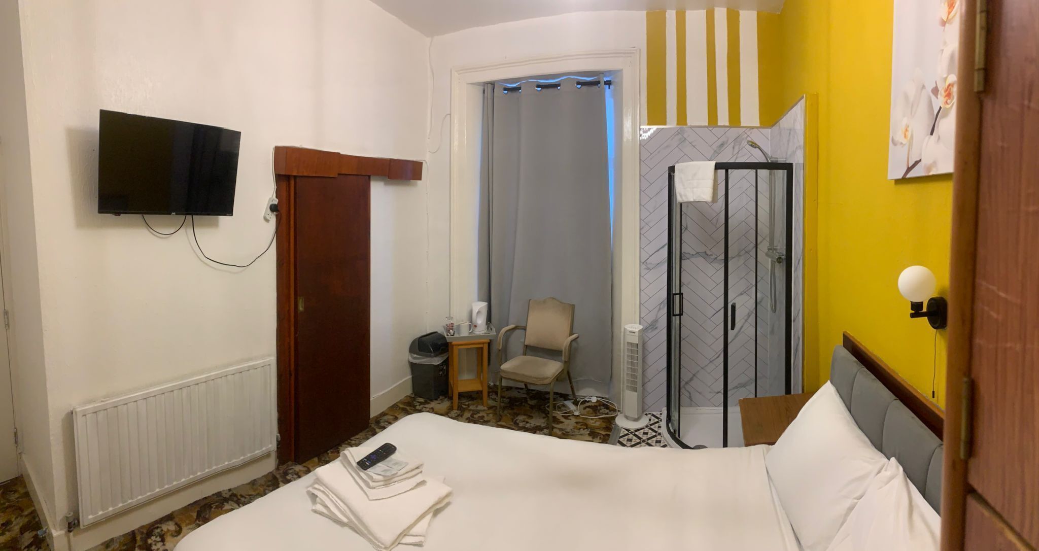 Une chambre d’hôtel avec un lit, une télévision, une douche et une chaise.