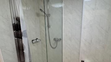 Un baño con ducha acristalada, inodoro y lavamanos.