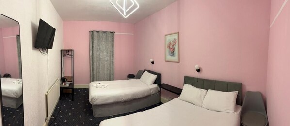 A hotel room with two beds, a mirror, a TV, a painting, and a window with curtains. - Savoy Hotel (Weston-super-Mare)