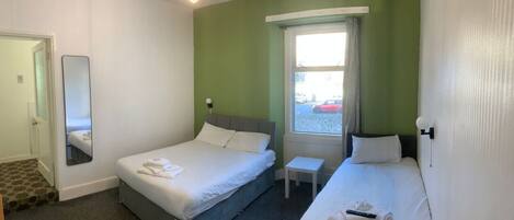 Een hotelkamer met twee bedden, een tafeltje, een spiegel en een raam met uitzicht.