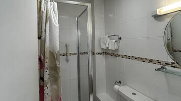 A bathroom with a shower, toilet, and sink, featuring a tiled floor and walls.
