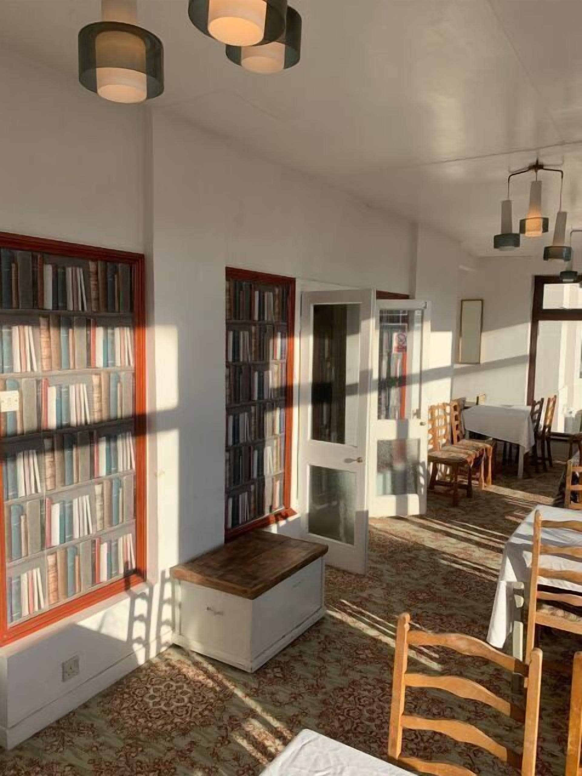 Un coin lecture confortable avec une bibliothèque intégrée, un petit espace salon et une table à manger avec des chaises.