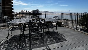 An outdoor seating area with a table and chairs, a decorative metal fence, and a view of the sea. - Savoy Hotel (Weston-super-Mare)