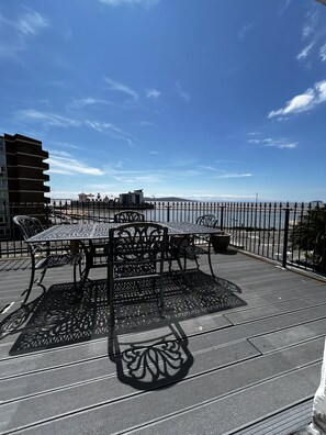 Un espacio al aire libre con mesa y sillas, una valla de metal decorativa y vistas al mar.