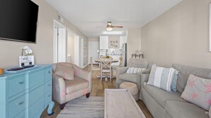 Un salon avec un canapé, une table basse et un téléviseur. Il y a également un coin repas avec une table et des chaises.