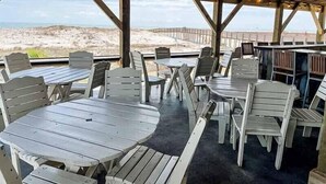 Une terrasse extérieure avec des tables et des chaises en bois, donnant sur une plage.