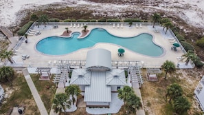 Un resort con una piscina grande, zonas de descanso y un edificio distintivo de techo curvo.