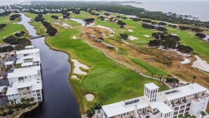 Vue aérienne d’un parcours de golf avec des bunkers, des obstacles d’eau et un pont.