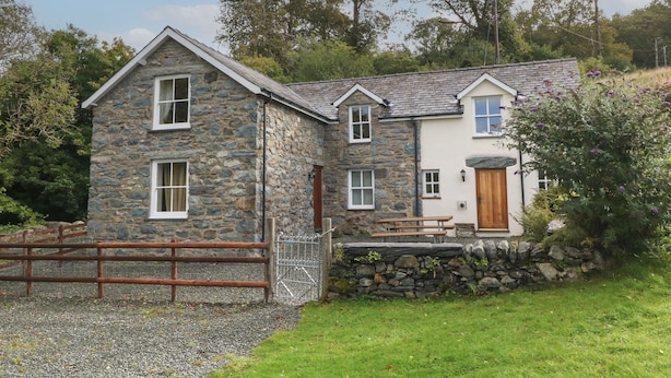 A stone house with a wooden door, a stone wall, and a gravel driveway. - Tyn Llwyn (Talsarnau)