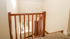 A wooden staircase with a handrail leading to a landing. - Tyn Llwyn (Talsarnau)