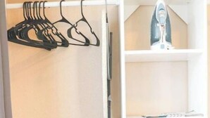 Een kamer met een witte kast, een droogrek en een klein strijkplank.
