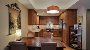 A modern kitchen with wooden cabinets, a stainless steel refrigerator, and a dining area with a wooden table and chairs. - Beautiful Space in the Heart of NW Portland's Alphabet District (Portland)