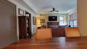 A dining area with a wooden table and chairs, a ceiling fan, and a television mounted on the wall. - Beautiful Space in the Heart of NW Portland's Alphabet District (Portland)