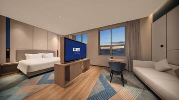 Een moderne hotelkamer met een bed, een televisie, een bank en een bureau.