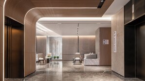 A modern lobby with a curved ceiling, a reception desk, seating area, and a wall-mounted elevator. - Holiday Inn Express Liaoyuan Economic Development Zone by IHG (Liaoyuan)