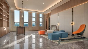 A modern interior with a polished floor, a wooden cabinet, a blue sofa, an orange chair, and a desk. - Holiday Inn Express Liaoyuan Economic Development Zone by IHG (Liaoyuan)