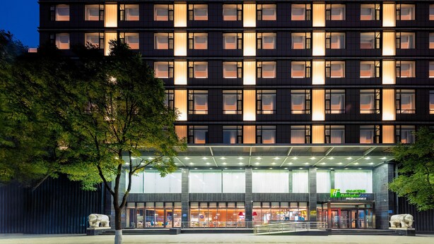Ein modernes Hotel mit Glasfassade, mehreren Stockwerken und einem gut beleuchteten Eingang.