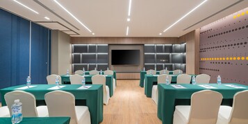 Una sala de conferencias con mesas, sillas y una pantalla grande.