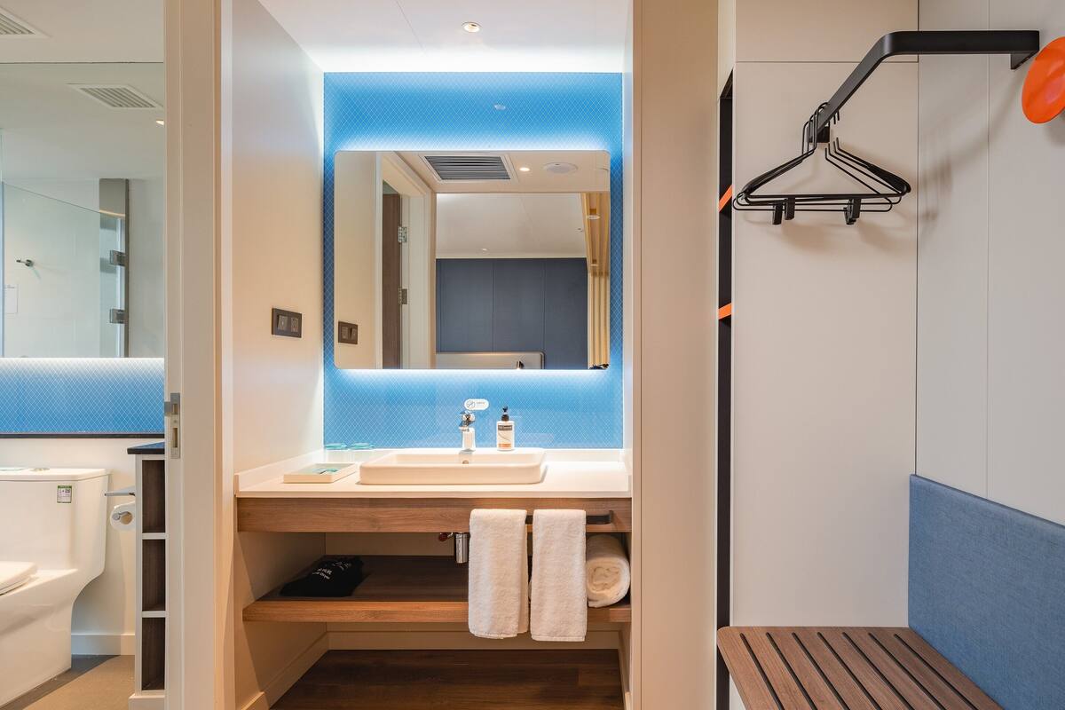 A modern bathroom with a white sink, mirror, and a shower area with a towel rack.