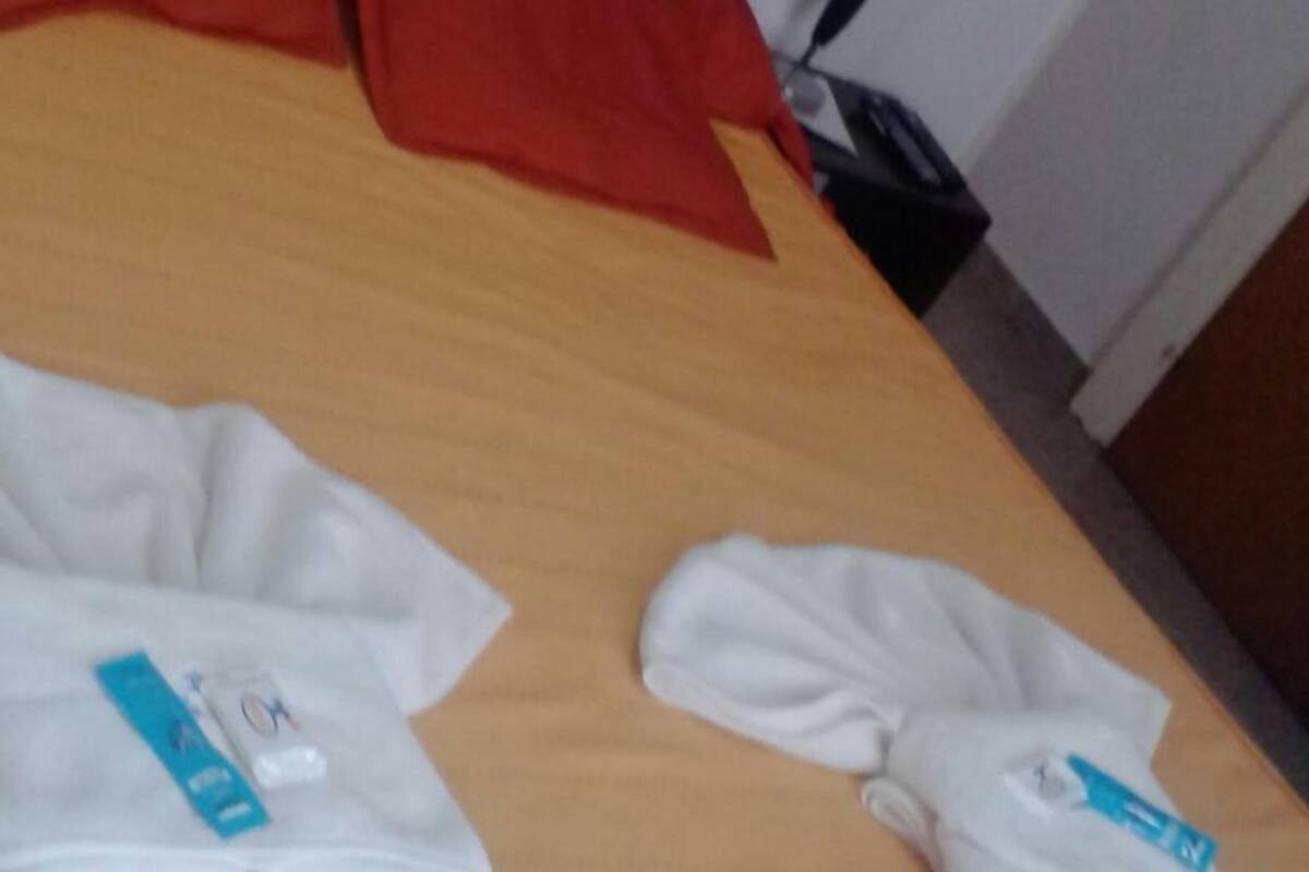 Una habitación de hotel con una cama de madera, almohadas rojas y toallas blancas sobre la cama.