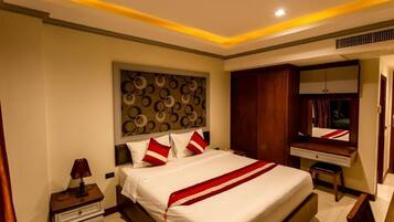 A hotel room with a large bed, a bedside table with a lamp, a wardrobe, and a mirror.