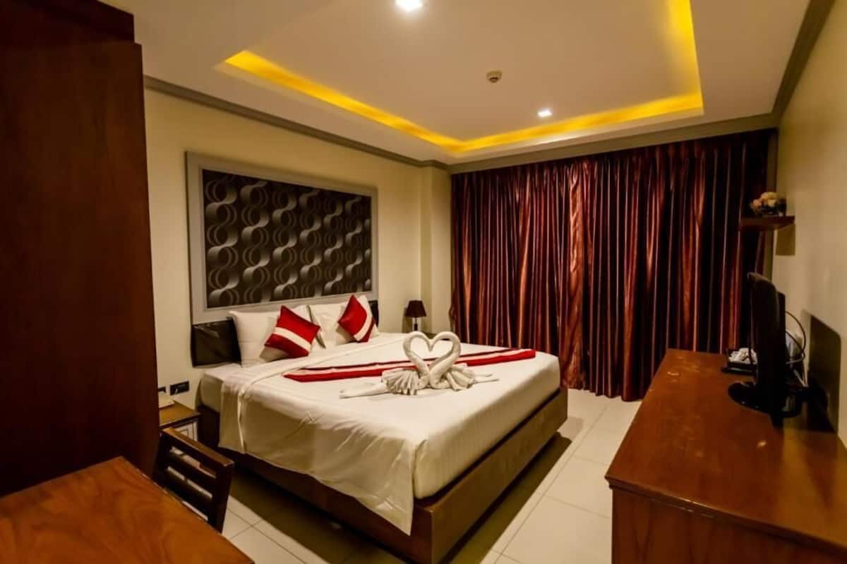 A hotel room with a bed, a desk, and a curtain.