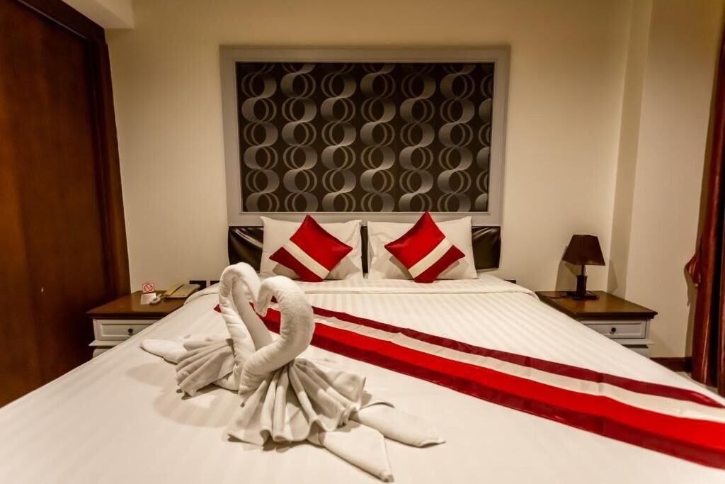 A hotel room with a bed, a headboard with a circular pattern, two nightstands, and a red and white striped bed runner.
