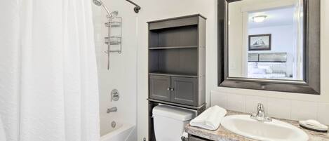 A bathroom with a shower, toilet, sink, and vanity.