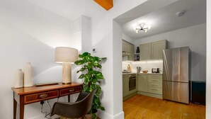 Une petite cuisine équipée d’un bureau en bois, d’une chaise, d’une lampe et d’une plante en pot.