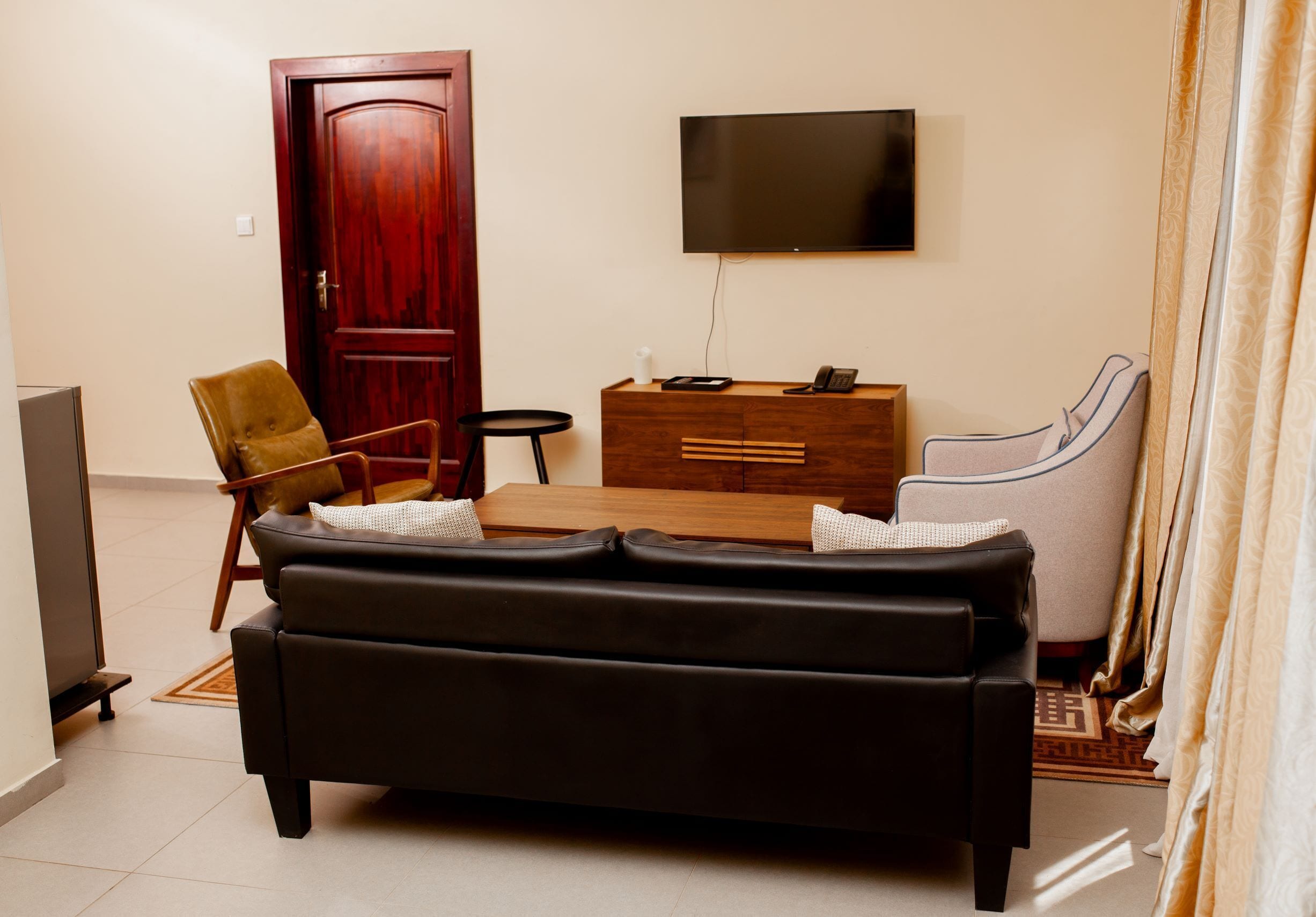 Un salon avec un canapé, un meuble en bois, une télévision et une porte.
