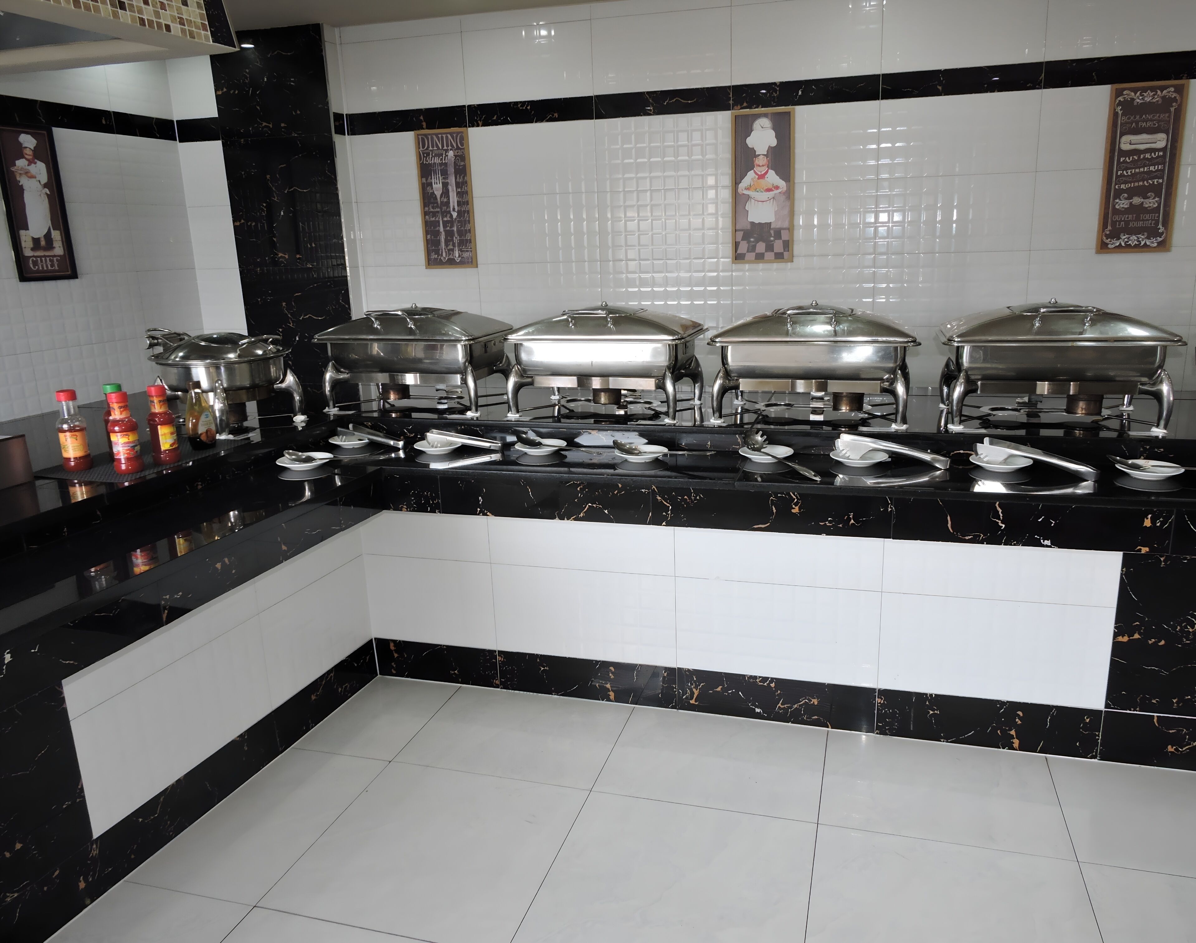 A buffet setup with multiple serving stations, including hot and cold food options, and condiments.