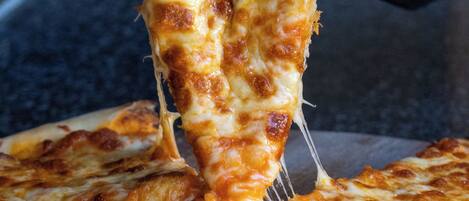 Una porción de pizza siendo retirada de una pizza entera.