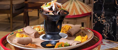 A traditional Ethiopian meal setup with injera, various stews, and a large black pot.
