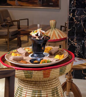 A traditional Ethiopian meal setup with injera, various stews, and a large black pot. - The Grand Palace Hotel (Lusaka)