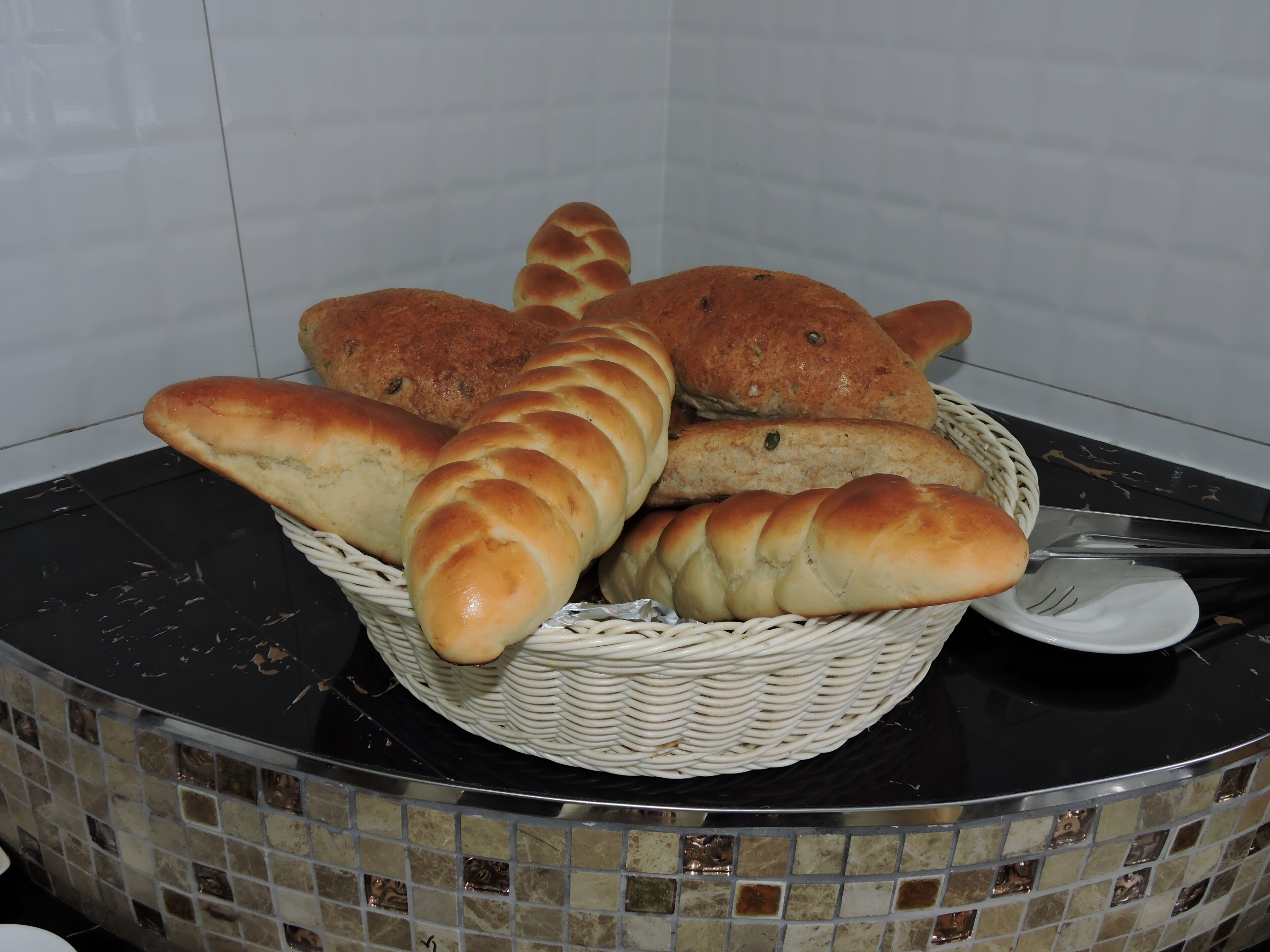 A basket of bread on a table with a tiled backsplash.