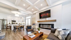 Una sala de estar moderna con chimenea, un comedor y una cocina al fondo.