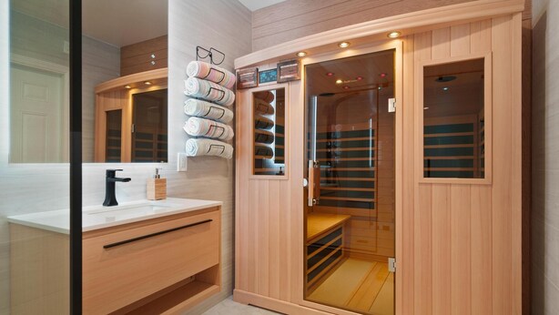 A modern bathroom with a wooden vanity, a glass shower enclosure, and neatly arranged towels. - Disney Explorer - Sauna, Theater, Arcade and More! (Garden Grove)