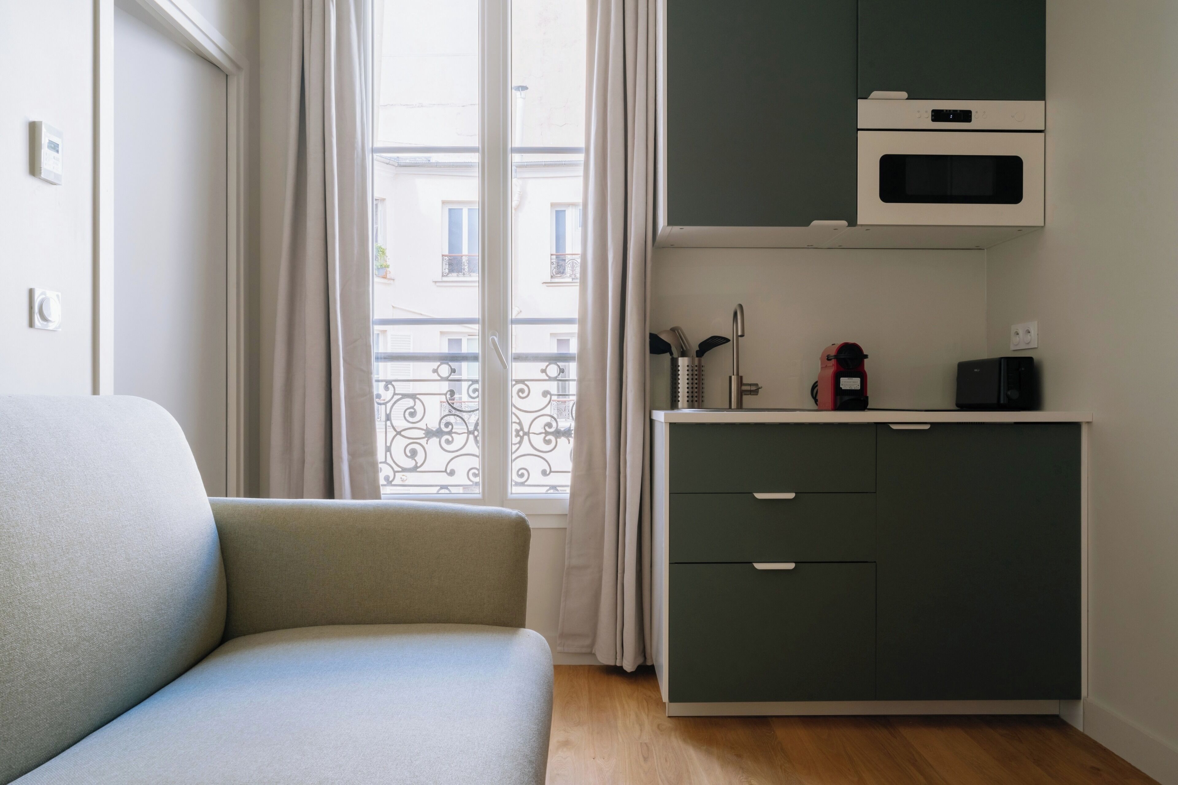 Une chambre avec un canapé, une kitchenette équipée d’un four à micro-ondes et donnant sur l’extérieur.