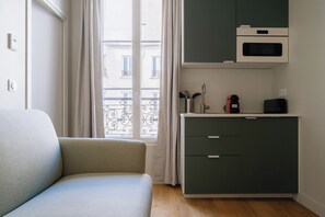Une chambre avec un canapé, une kitchenette équipée d’un four à micro-ondes et donnant sur l’extérieur.