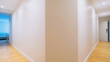 Un couloir doté d’un plancher en bois, d’un mur bleu et d’une porte donnant sur une autre pièce.