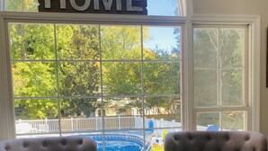Una habitación con dos sillones, una mesita y un amplio ventanal con un cartel que dice 'HOME'.