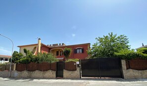 Ein zweistöckiges Haus mit roter Fassade, einer Steinmauer und einem Holzzaun.
