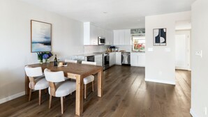 A modern kitchen with white cabinets, stainless steel appliances, and a wooden dining table with chairs.