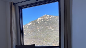 A room with a large window overlooking a mountainous landscape.
